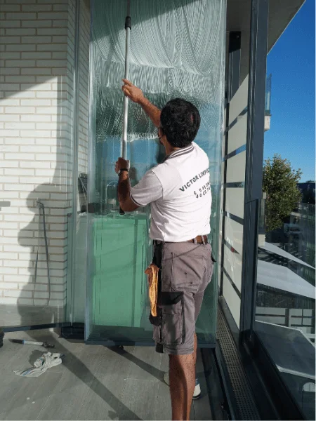 Trabajador de empresa de limpieza en Majadahonda limpiando cristal exterior en terraza con pértiga